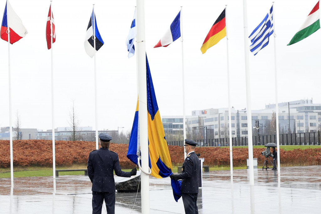 Dvaja vojaci sa pripravujú na vztýčenie švédskej vlajky počas slávnostného ceremoniálu pri príležitosti vstupu Švédska do NATO.  FOTO: TASR/AP