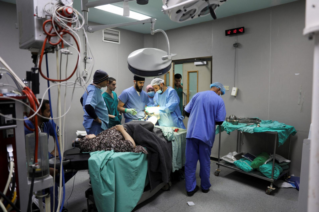 Plastický chirurg a lekár Thaer Daifallah ošetrujú palestínsku ženu zranenú pri izraelskom údere v nemocnici v Chán Júnise na juhu Pásma Gazy. FOTO: Reuters