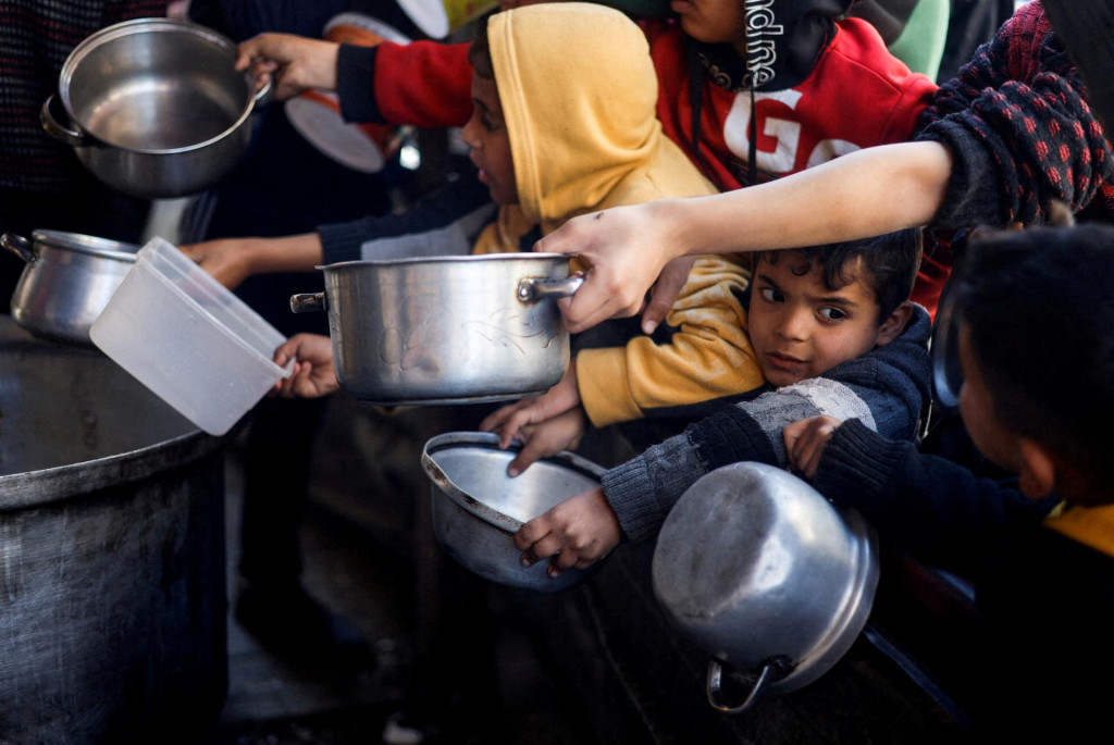 Palestínske deti čakajú, kým dostanú jedlo uvarené v charitatívnej kuchyni v Rafahu. FOTO: Reuters