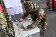 Ruský vojak odovzdáva svoj hlas vo volebnej miestnosti počas predčasného hlasovania pre nadchádzajúce ruské prezidentské voľby na Ruskom okupovanej časti Záporožskej oblasti na východe Ukrajiny. FOTO: TASR/AP
