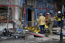 Hasiči stoja pri poškodenej budove v ruskom Belgorode. FOTO: TASR/AP