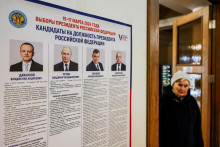 Žena prechádza okolo tabule s informáciami o kandidátoch vo volebnej miestnosti počas ruských prezidentských volieb vo Vidnoje. FOTO: Reuters