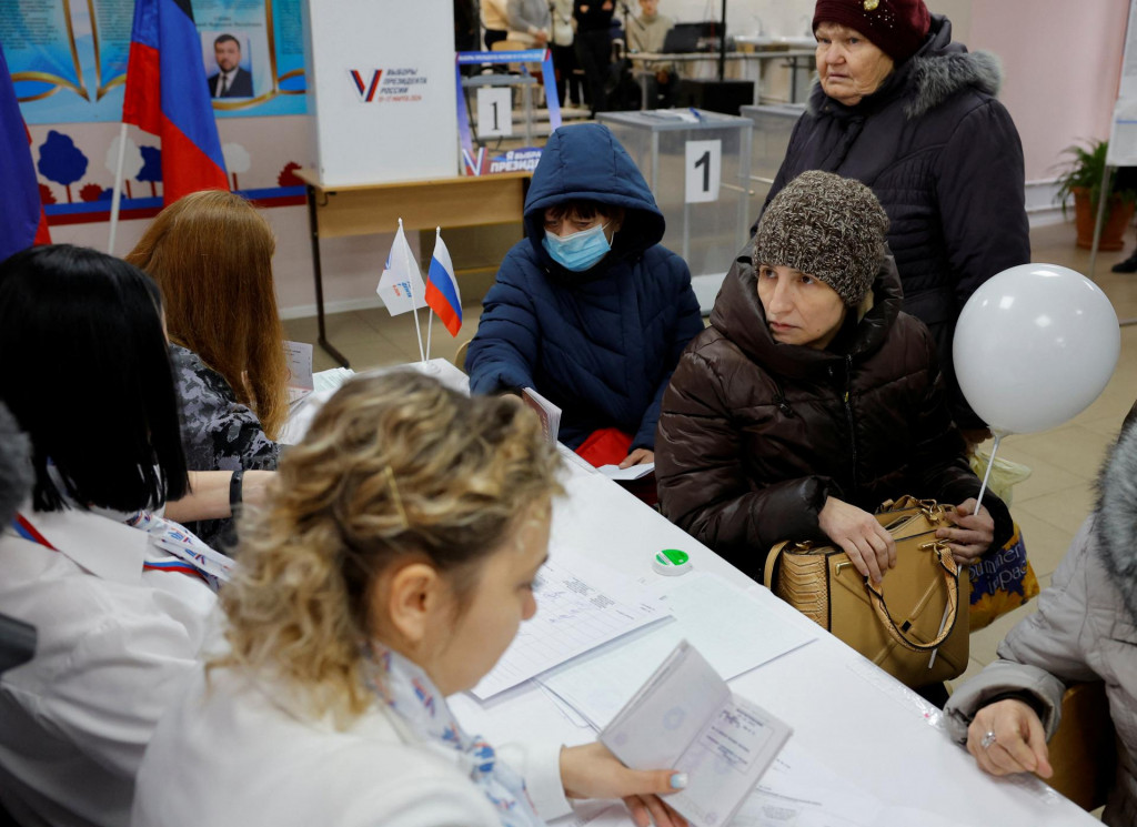 Obyvatelia Avdiivky, ktorí teraz bývajú v dočasnom ubytovacom zariadení, dostávajú hlasovacie lístky vo volebnej miestnosti počas ruských prezidentských volieb na Ukrajine ovládanej Ruskom. FOTO: Reuters