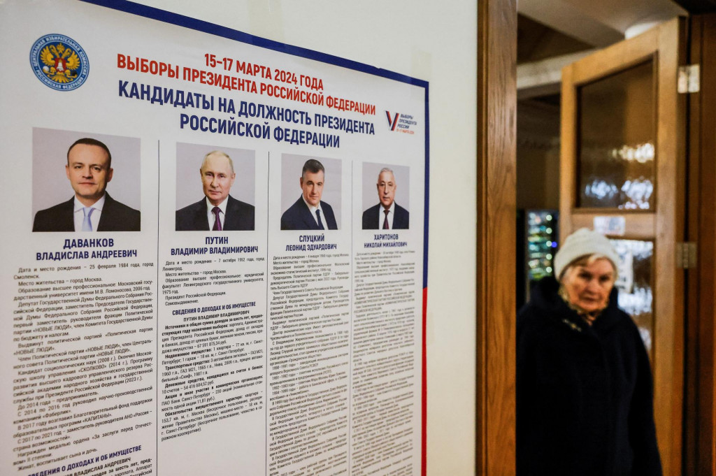 Žena prechádza okolo tabule s informáciami o kandidátoch vo volebnej miestnosti počas ruských prezidentských volieb vo Vidnoje. FOTO: Reuters
