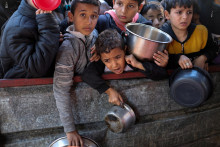 Palestínske deti čakajú, kým dostanú jedlo uvarené v charitatívnej kuchyni v Rafahu v južnom Pásme Gazy. FOTO: Reuters