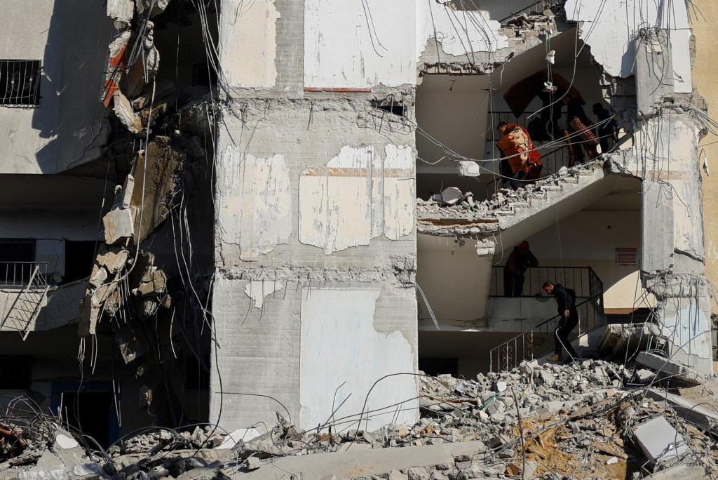 Palestínčania nesú veci na mieste izraelského leteckého útoku na budovu v Rafahu v južnom Pásme Gazy. FOTO: Reuters
