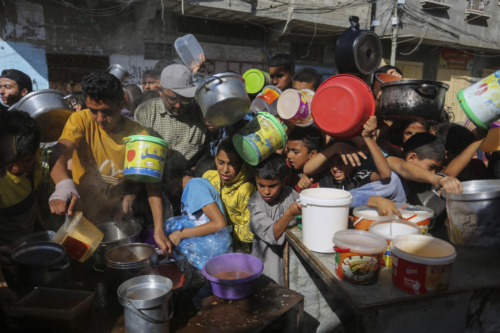 Palestínčania stoja v rade a čakajú na distribúciu jedla v meste Rafah v Pásme Gazy. FOTO: TASR/AP