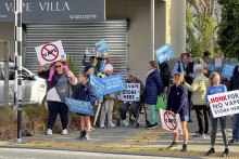 Na archívnej snímke z 1. augusta 2023 ľudia protestujú pred školou v Aucklande, v blízkosti ktorej sa mal otvoriť obchod s elektronickými cigaretami. FOTO: TASR/AP