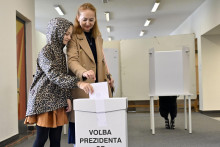 Žena s dieťaťom vhadzuje obálku s hlasovacím lístkom do volebnej schránky v prvom kole prezidentských volieb v novej volebnej miestnosti v športovej hale v Michalovciach. FOTO: TASR/Roman Hanc