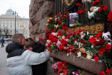 Pár sa objíma pri provizórnom pamätníku obetiam útoku na koncertnom centre Crocus City Hall pri Moskve. FOTO: Reuters