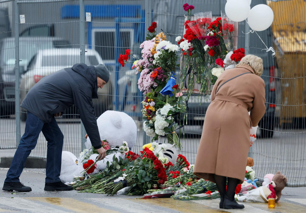 Ľudia kladú kvety k provizórnemu pamätníku obetiam útoku v koncertnej sále Crocus City Hall pri Moskve. FOTO: Reuters