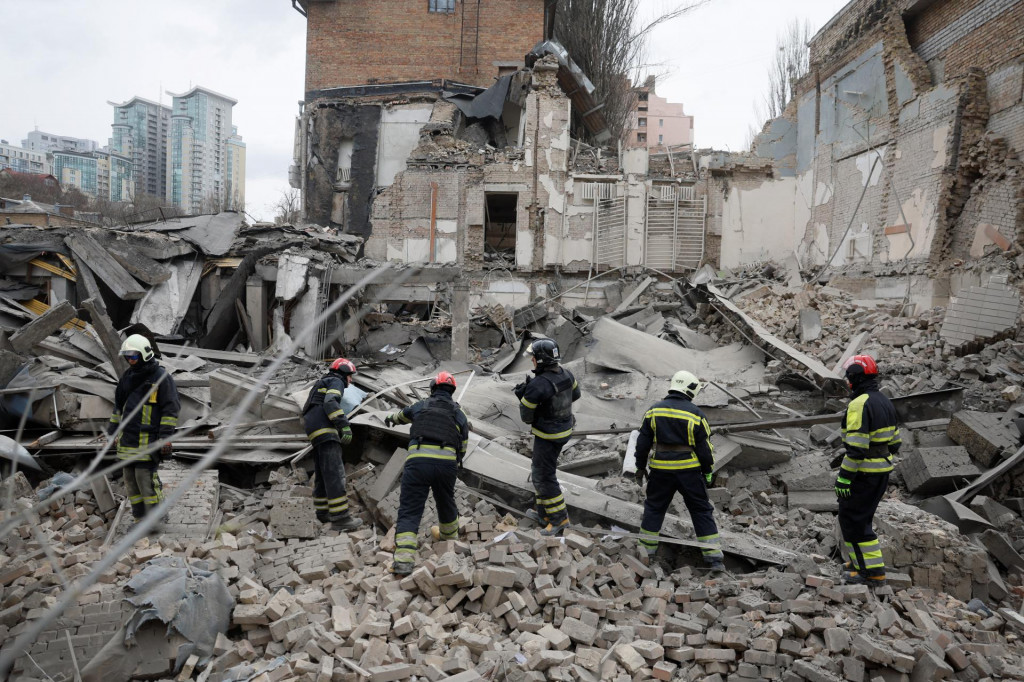 Záchranári pracujú na mieste budovy poškodenej ruským raketovým útokom v Kyjeve. FOTO: Reuters