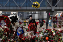 Po útoku na mieste koncertnej sále pri Moskve stráži policajt pri provizórnom pamätníku. FOTO: Reuters