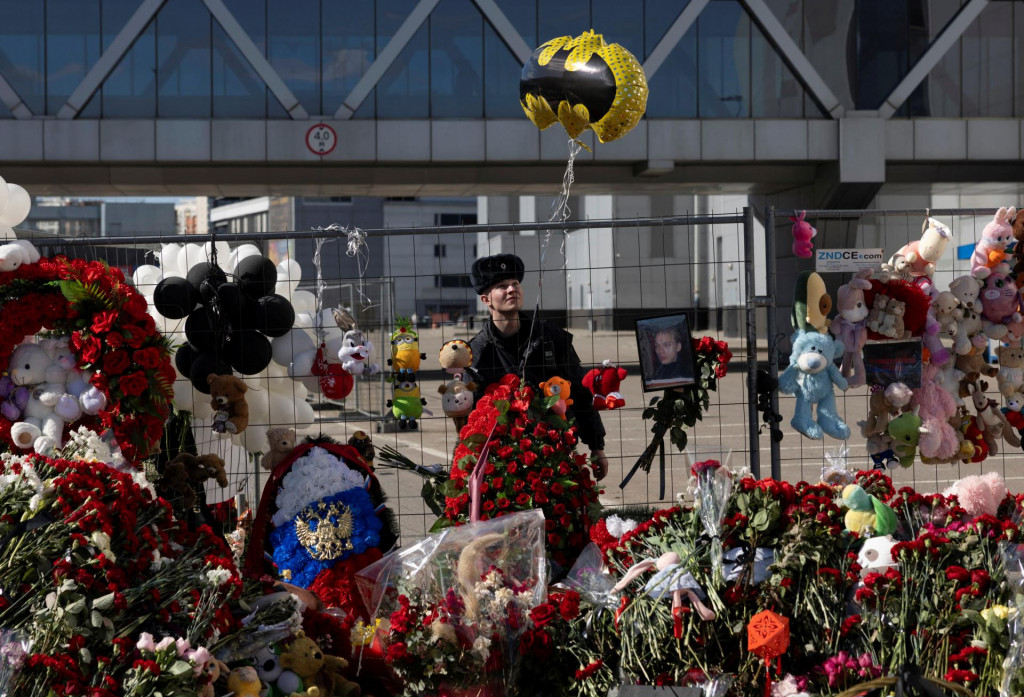 Po útoku na mieste koncertnej sále pri Moskve stráži policajt pri provizórnom pamätníku. FOTO: Reuters