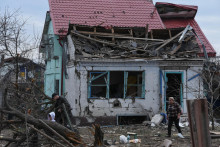Miestni obyvatelia kráčajú vedľa svojho domu poškodeného počas útoku ruskej rakety a dronu v meste Kamianske. FOTO: Reuters