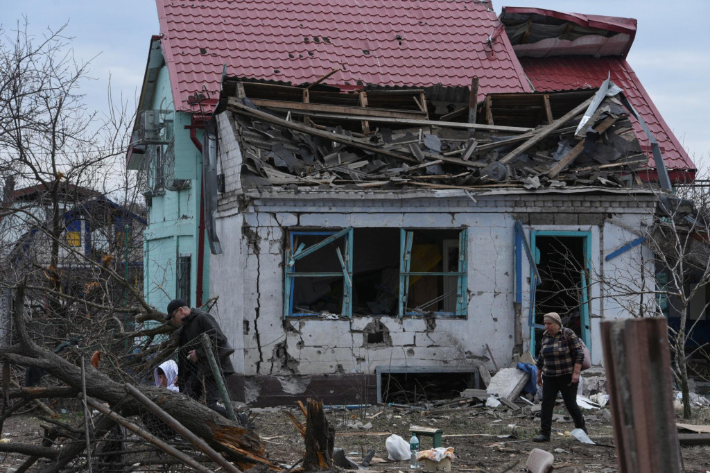 Miestni obyvatelia kráčajú vedľa svojho domu poškodeného počas útoku ruskej rakety a dronu v meste Kamianske. FOTO: Reuters
