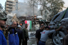 Ľudia sa zhromažďujú neďaleko poškodeného miesta a odvážajú zničené vozidlo po izraelskom leteckom útoku na iránsky konzulát v sýrskom hlavnom meste Damask. FOTO: Reuters