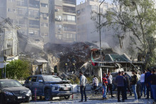 Ľudia zhromaždení pred poškodenou budovou po leteckom útoku v Damasku. FOTO TASR/AP