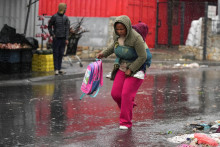 Žena v Kapskom meste nesie domov dieťa, aby ho uchránila pred silným dažďom a mohutným vetrom. FOTO: Reuters
