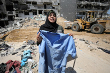 Palestínska žena drží svoje oblečenie, zatiaľ čo záchranári a zdravotníci pátrajú po mŕtvych telách v poškodenej nemocnici. FOTO: Reuters