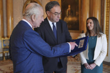 Britský kráľ Karol III. si prezerá prvé bankovky so svojím portrétom, ktoré mu priniesli guvernér britskej centrálnej banky Andrew Bailey a hlavná pokladníčka BoE Sarah Johnová. FOTO: TASR/AP