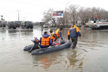 Záchranári jazdia na člne po zaplavenej ulici v Orsku v Rusku. FOTO: Reuters