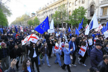 Demonštranti kráčajú počas protestu proti návrhu zákona o zahraničných agentoch pred budovou parlamentu v Tbilisi. FOTO: TASR/AP