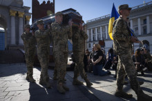 Ľudia kľačia, keď vojaci nesú rakvy ukrajinských vojakov Serhija Konovala a Tarasa Petrušuna, ktorí zahynuli v boji s ruskými vojakmi počas pohrebu na Námestí nezávislosti v Kyjeve. FOTO: TASR/AP