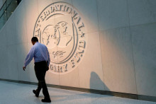 Muž kráča pred logom Medzinárodného menového fondu. ILUSTRAČNÉ FOTO: REUTERS