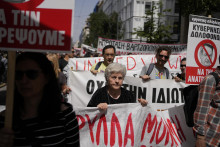 Protestujúci držia transparenty počas zhromaždenia v Aténach. FOTO: TASR/AP