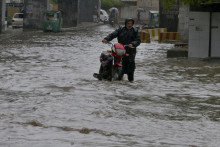Pakistanec tlačí svoj motocykel cez zaplavenú cestu po prudkých dažďoch v pakistanskom meste Pešávar. FOTO: TASR/AP