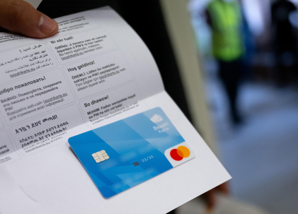 Žiadateľ o azyl ukazuje platobnú kartu v Mníchove. Nemecký parlament v piatok 12. apríla schválil zákon o platobnej karte pre utečencov a uchádzačov o azyl. Karta bude platná v celej krajine. Bude na ňu odchádzať časť štátnych dávok vo forme kreditu, ktorý nahradí hotovosť. Jedným z účelov nového systému je zabrániť, aby utečenci posielali peniaze prevádzačom alebo rodine a priateľom v zahraničí. FOTO: TASR/DPA