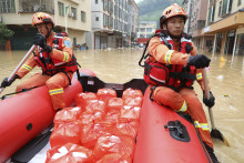 Záchranári roznášajú na člne ľuďom potraviny v zaplavenom meste Lien-ťien-kchou v provincii Kuang-tung na juhu Číny.