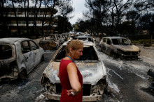 Miestny obyvateľ stojí vedľa spálených áut po lesnom požiari v dedine Mati, 24. júla 2018. FOTO: Reuters