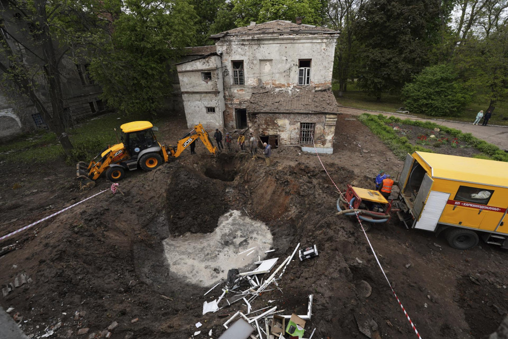 Pracovníci mestských služieb kopú bagrom v blízkosti krátera po ruskom útoku na psychiatrickú nemocnicu, ktorý poškodil telekomunikačné vedenie v meste Charkov. FOTO: TASR/AP