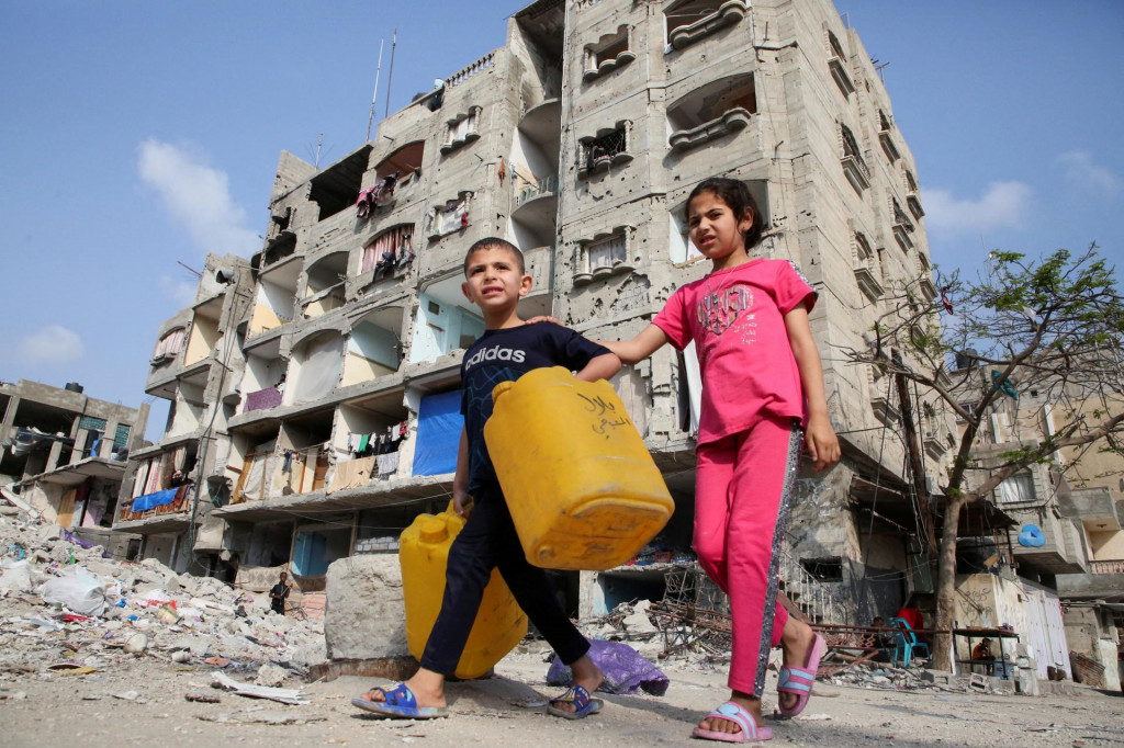 Palestínske deti prechádzajú okolo domu poškodeného pri izraelskom údere v Rafahu. FOTO: Reuters