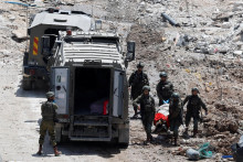 Izraelskí vojaci nesú telo na nosidlách v blízkosti vojenského vozidla počas izraelského náletu v Deir al-Ghusun na Izraelom okupovanom Západnom brehu Jordánu. FOTO: Reuters