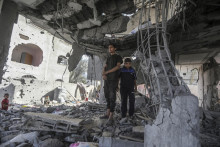 Palestínčania stoja v ruinách rodinnégo domu po nočnom leteckom útoku izraelskej armády v meste Rafah na juhu Pásma Gazy. FOTO: TASR/AP