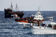 Plavidlo talianskej pobrežnej stráže prevážajúce migrantov zachránených na mori prechádza medzi turistickými člnmi na sicílskom ostrove Lampedusa. FOTO: Reuters