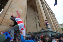 Demonštranti s gruzínskou vlajkou sa zúčastňujú na proteste proti návrhu zákona o „zahraničných agentoch“ pred budovou parlamentu v Tbilisi. FOTO: Reuters