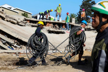 Záchranári pracujú na záchrane stavebných robotníkov uväznených pod budovou, ktorá sa zrútila v juhoafrickom meste George. FOTO: Reuters