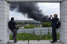 Zahraniční novinári sa hlásia z pozorovateľne, zatiaľ čo stúpa dym po ruskom útoku v Charkove na Ukrajine. FOTO TASR/AP