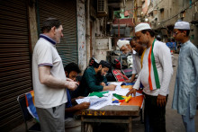 Ľudia si kontrolujú svoje mená v zozname voličov pred volebnou miestnosťou v deň šiestej fázy volieb v Dillí. FOTO: Reuters