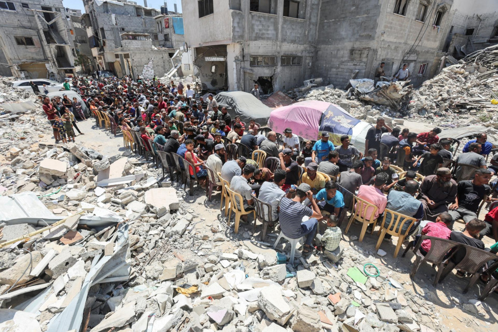 Palestínčania jedia jedlo varené v charitatívnej kuchyni v blízkosti domov zničených pri izraelskej vojenskej ofenzíve. FOTO: Reuters