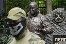Vojak súkromnej žoldnierskej Vagnerovej skupiny so zakrytou tvárou stojí pri bronzovej soche ruského prokremeľského žoldniera a oligarchu Jevgenija Prigožina, ktorú odhalili na jeho hrobe na Porochovskom cintoríne v Petrohrade. FOTO TASR/AP
