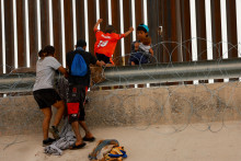 Migranti sa pokúšajú prekročiť plot z ostnatého drôtu, ktorý im má brániť v prechode do Spojených štátov, ako je vidieť z mesta Ciudad Juarez v Mexiku. FOTO: REUTERS