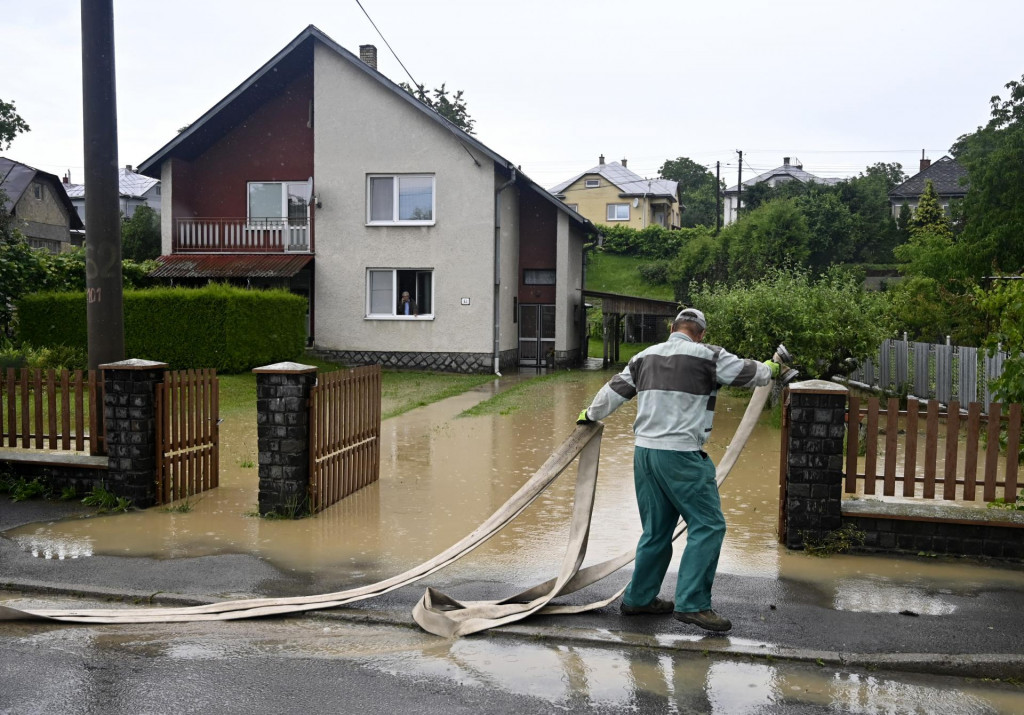 Muž odčerpáva vodu z dvora rodinného domu po silnom prívalovom daždi v obci Kamenná Poruba v okrese Vranov nad Topľou v utorok 4. júna 2024.