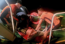 Záchranári pobrežnej stráže nesú preživšieho z plavidla, ktoré zachvátil požiar v blízkosti vôd pri meste Naga v provincii Cebu na Filipínachv. FOTO: TASR/AP