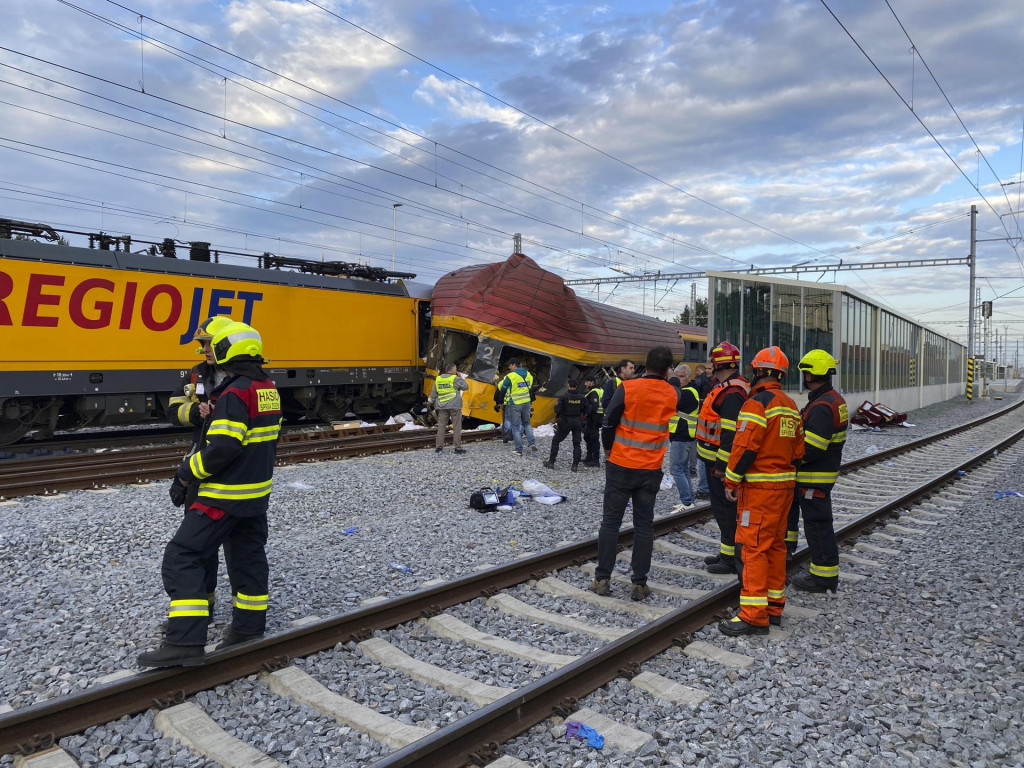 Hasiči stoja vedľa dvoch vlakov po zrážke v Pardubiciach. FOTO: TASR/AP