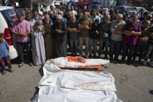 Palestínčania sa modlia pri telách ľudí zabitých po izraelskom bombardovaní Pásma Gazy pred nemocnicou v meste Deir al Balah. FOTO: TASR/AP